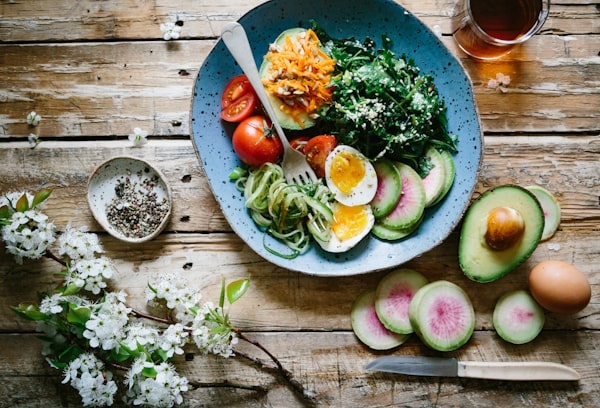 A fresh healthy bowl with leafy greens, egg, avocado, tomato and radish